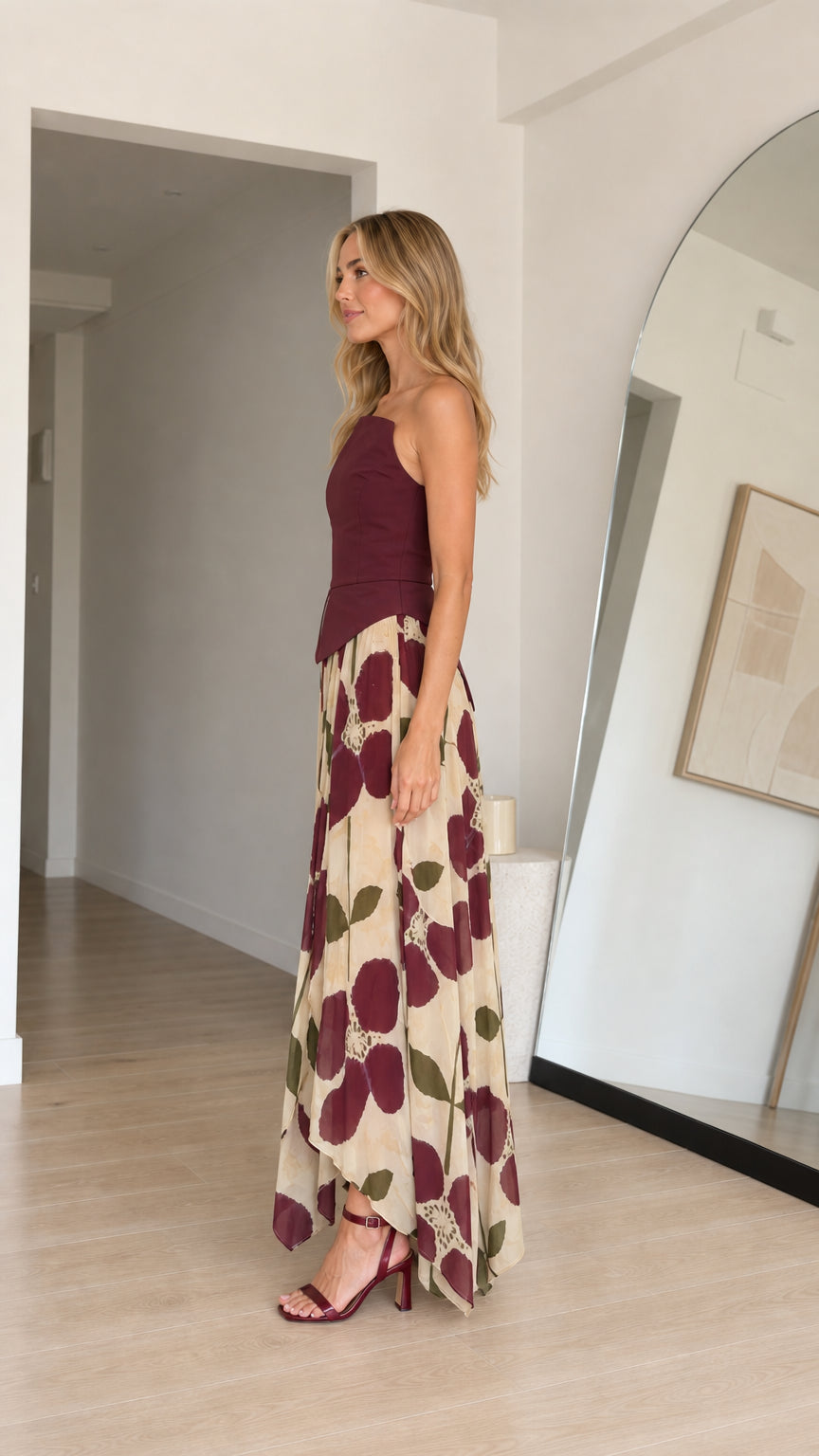 Side profile of model in burgundy strapless floral dress