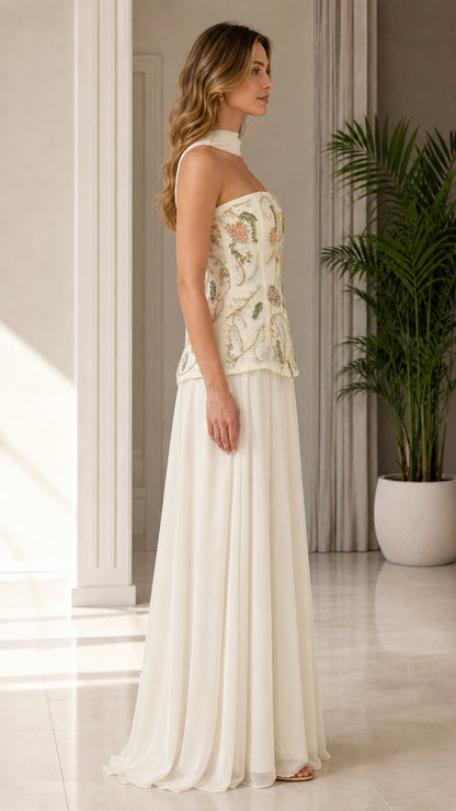 Side profile of model wearing ivory floral embroidered corset dress with flowing maxi skirt