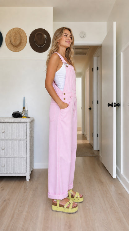 Side view of pink women's bib overalls showing the relaxed wide-leg fit and utility pockets