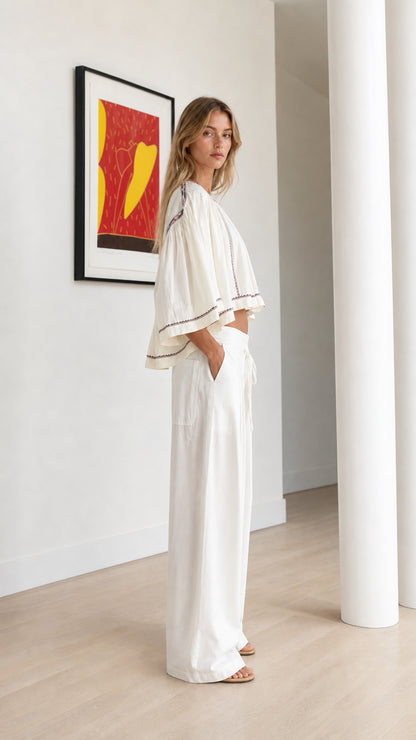Side profile view of off-white boho embroidered crop top with wide flowing sleeves