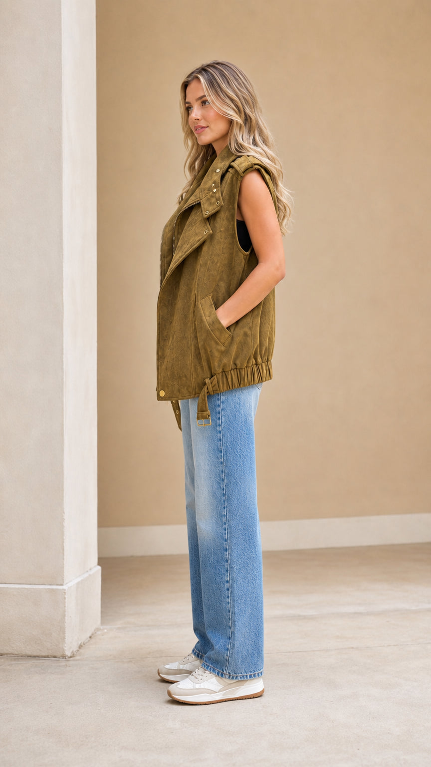 Side profile view of woman wearing sleeveless olive green suede biker vest