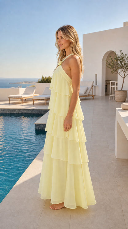 Side profile view of light yellow tiered flowy maxi dress poolside