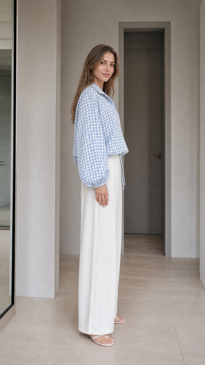 Woman wearing light blue gingham check blouse, side profile view