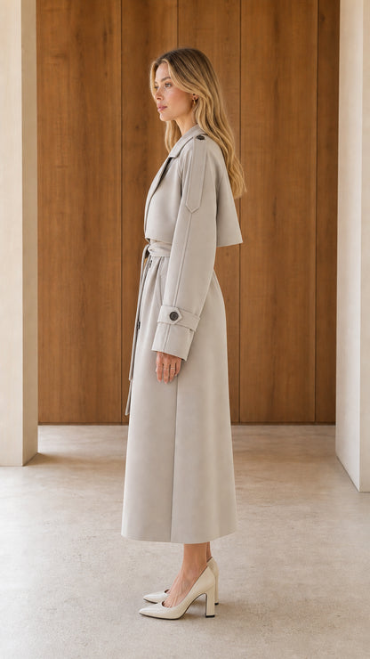 Side profile view of woman wearing a light grey maxi trench coat