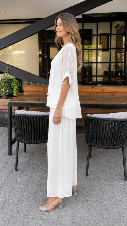Model wearing white layered tunic set, side profile