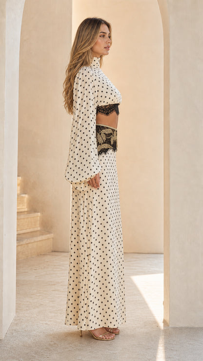 Side view of woman wearing cream polka dot crop top and high-waisted maxi skirt set