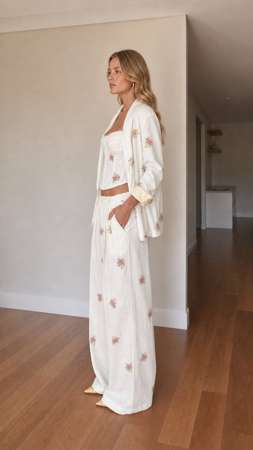 Side angle view of woman wearing cream embroidered 3-piece blazer and pant set