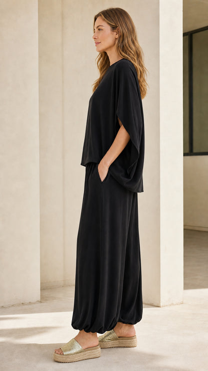 Side profile of woman wearing black matching set with sandals