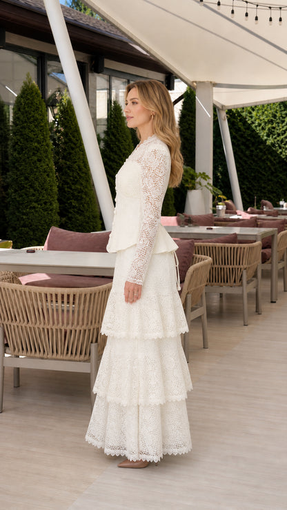 Side profile of woman in ivory tiered lace evening gown with peplum waist
