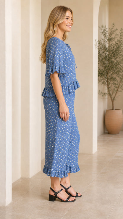 Side view of model wearing blue floral ruffle top and wide-leg cropped pants set