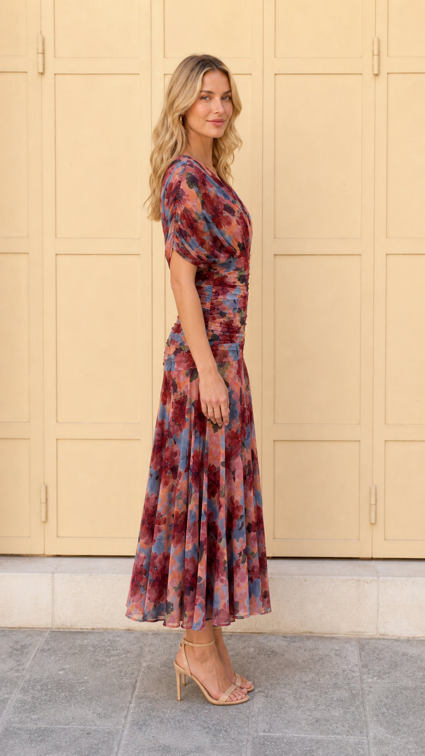 Side profile view of woman in multi pink floral ruched midi dress
