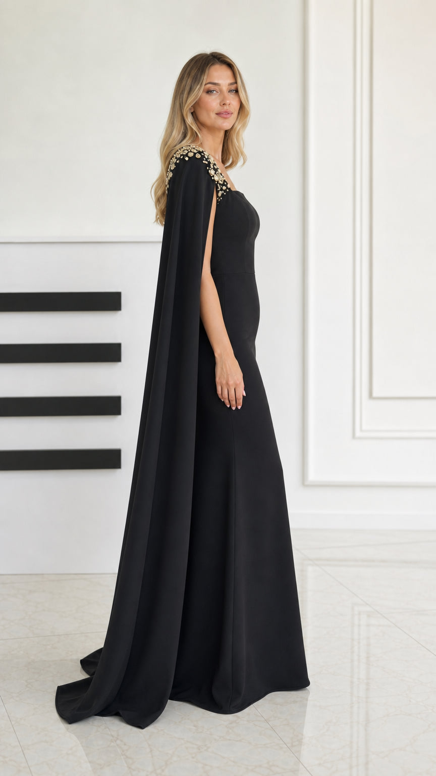 Side profile of black cape sleeve evening gown showing elegant floor length drape