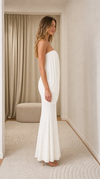Model wearing white strapless draped maxi dress, side view