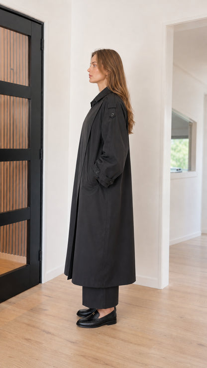 Side profile view of oversized black long trench coat with dropped shoulders