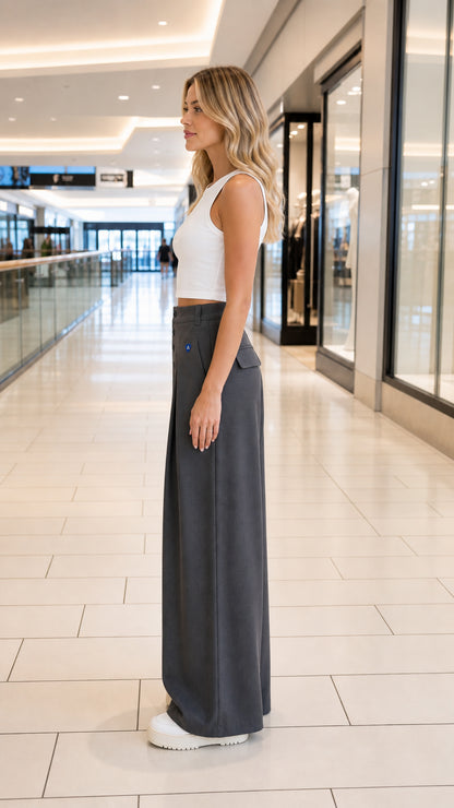 Side profile view of model wearing charcoal grey pleated wide-leg trousers