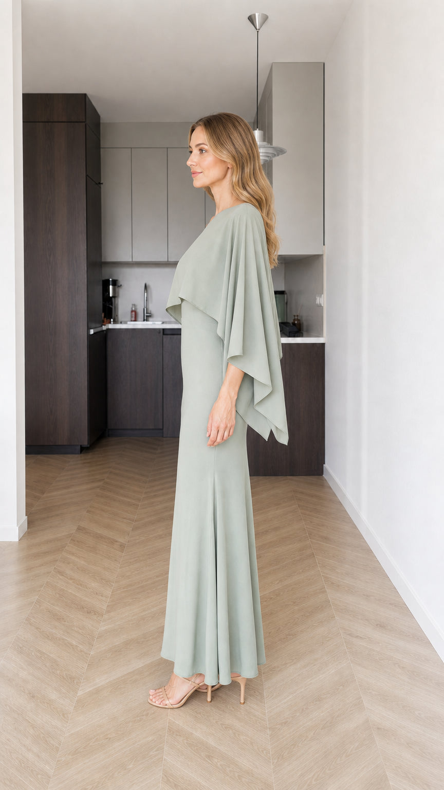 Side profile view of model in sage green cape maxi dress