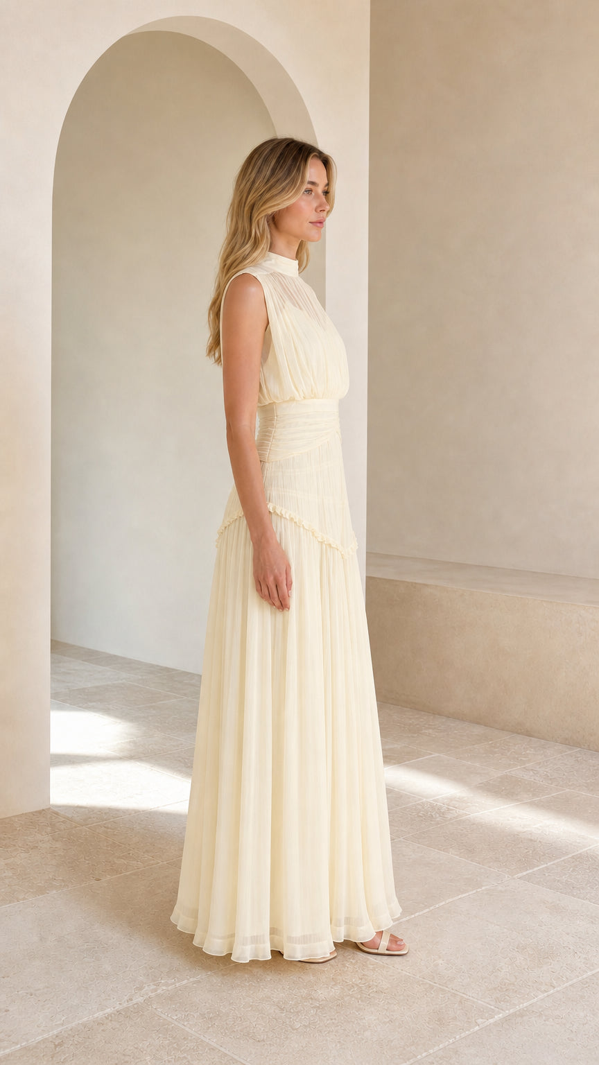 Side profile view of model in cream pleated sleeveless maxi dress