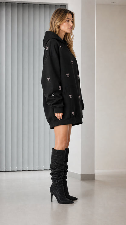 Side profile of model in black rhinestone bow hoodie dress