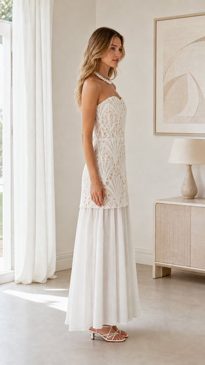 Side profile of model wearing white strapless lace bodice drop waist dress