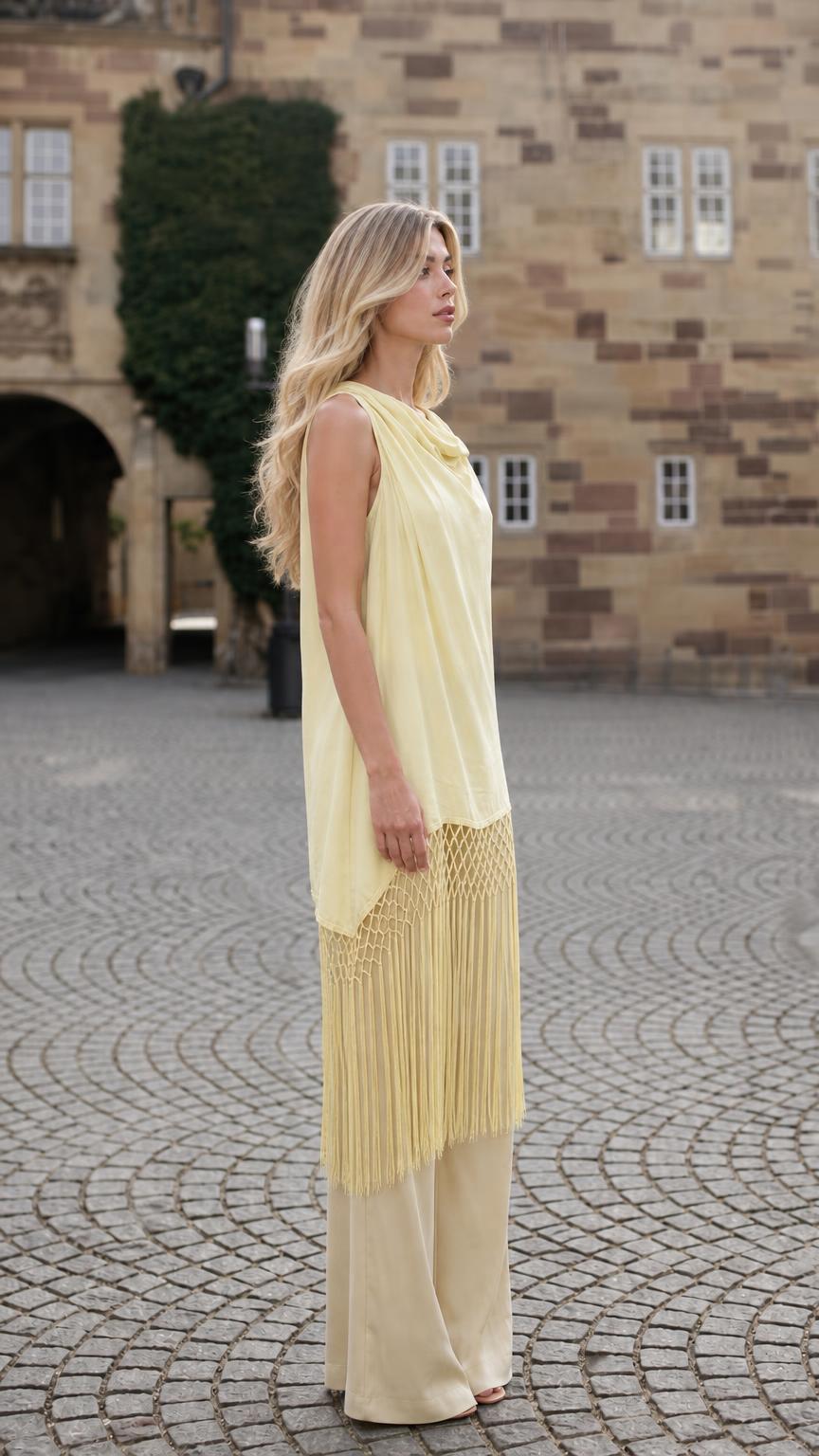 Side profile of model in yellow fringe tunic outdoors