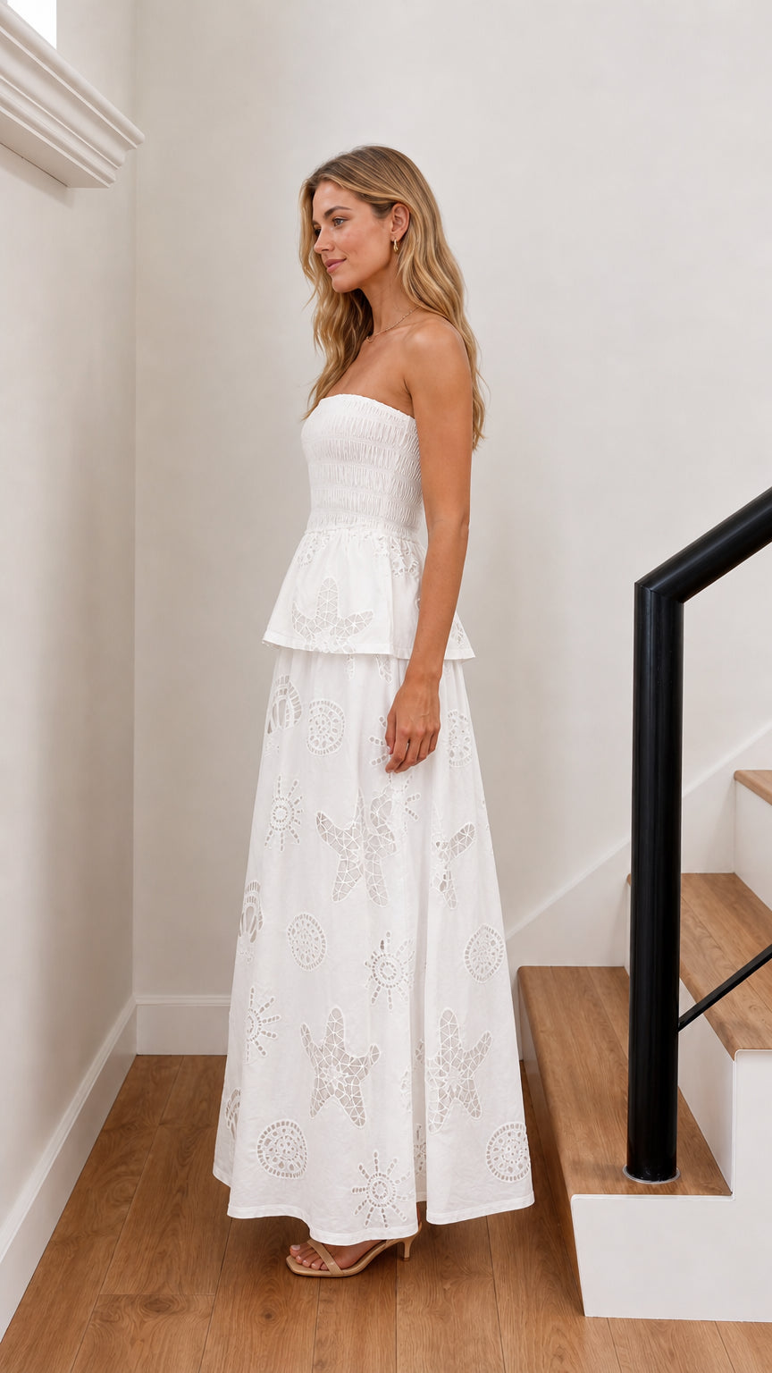 Side profile of model in white strapless maxi dress