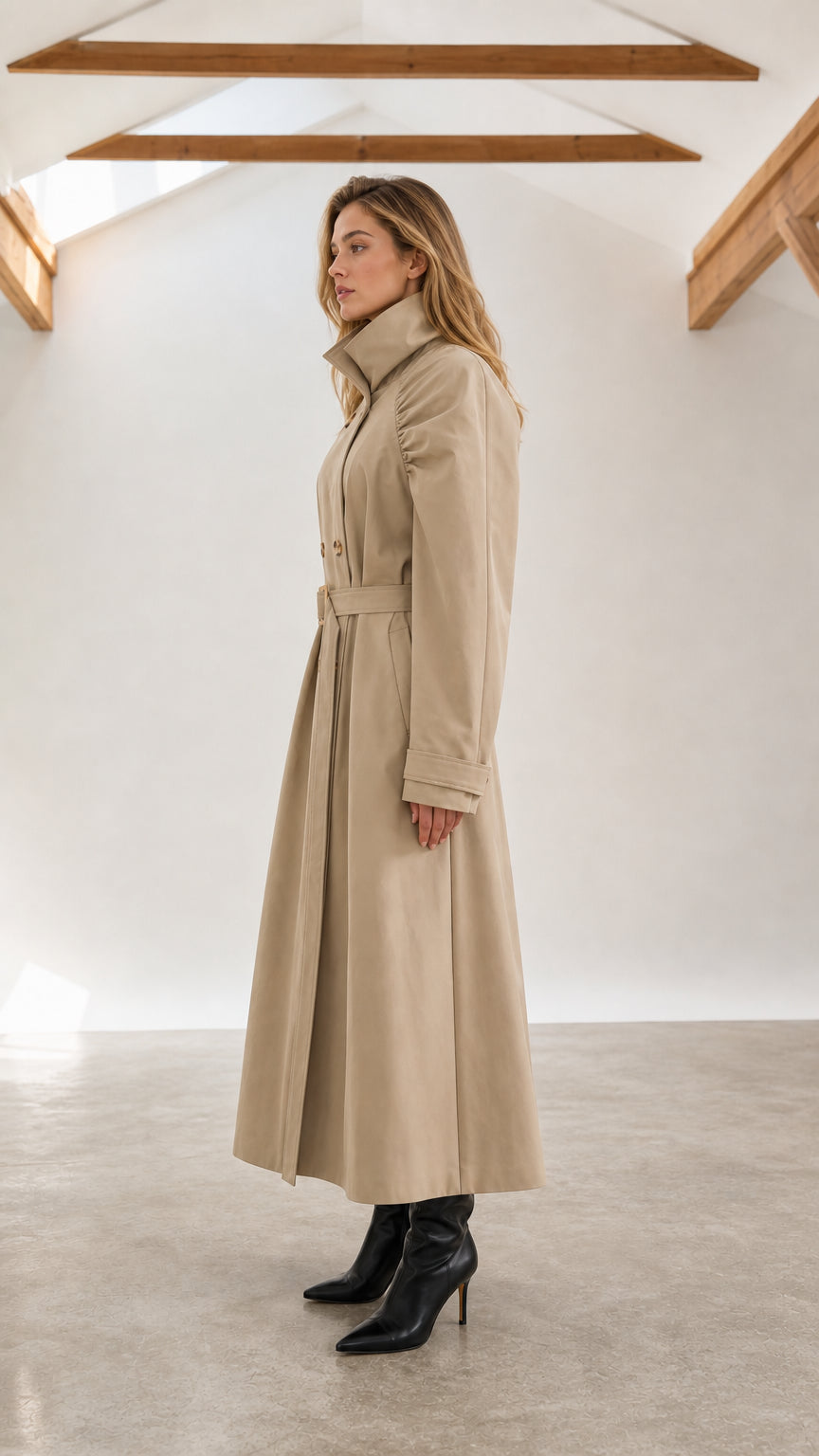 Side profile view of woman wearing beige double-breasted long belted trench coat
