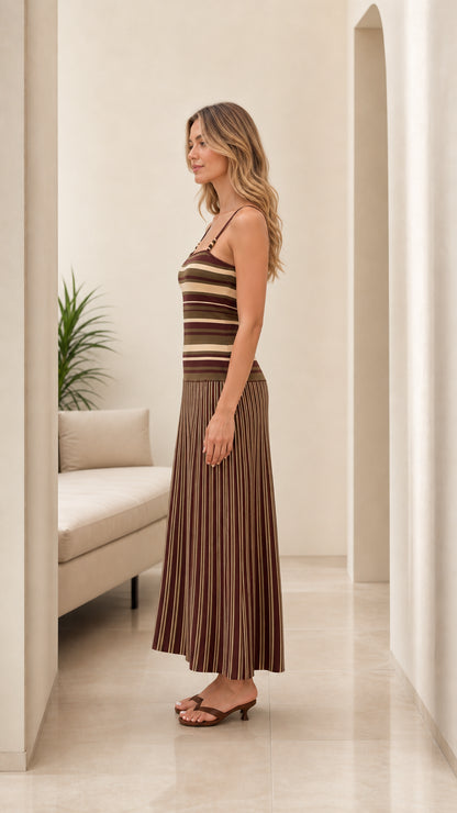 Side view of woman wearing brown striped knit maxi dress showing drop-waist pleated skirt