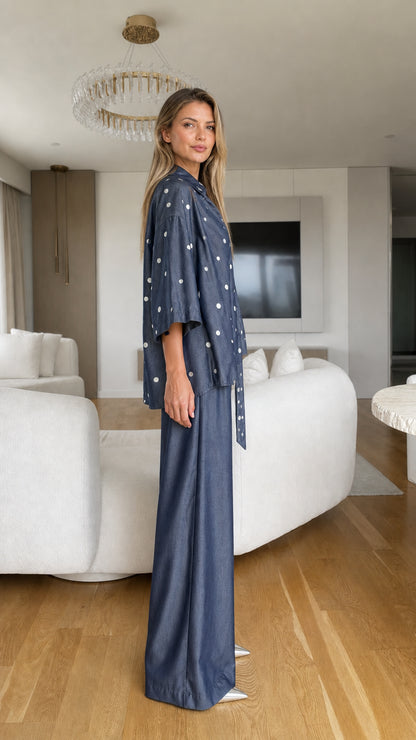 Model wearing denim blue polka dot two-piece outfit side profile view