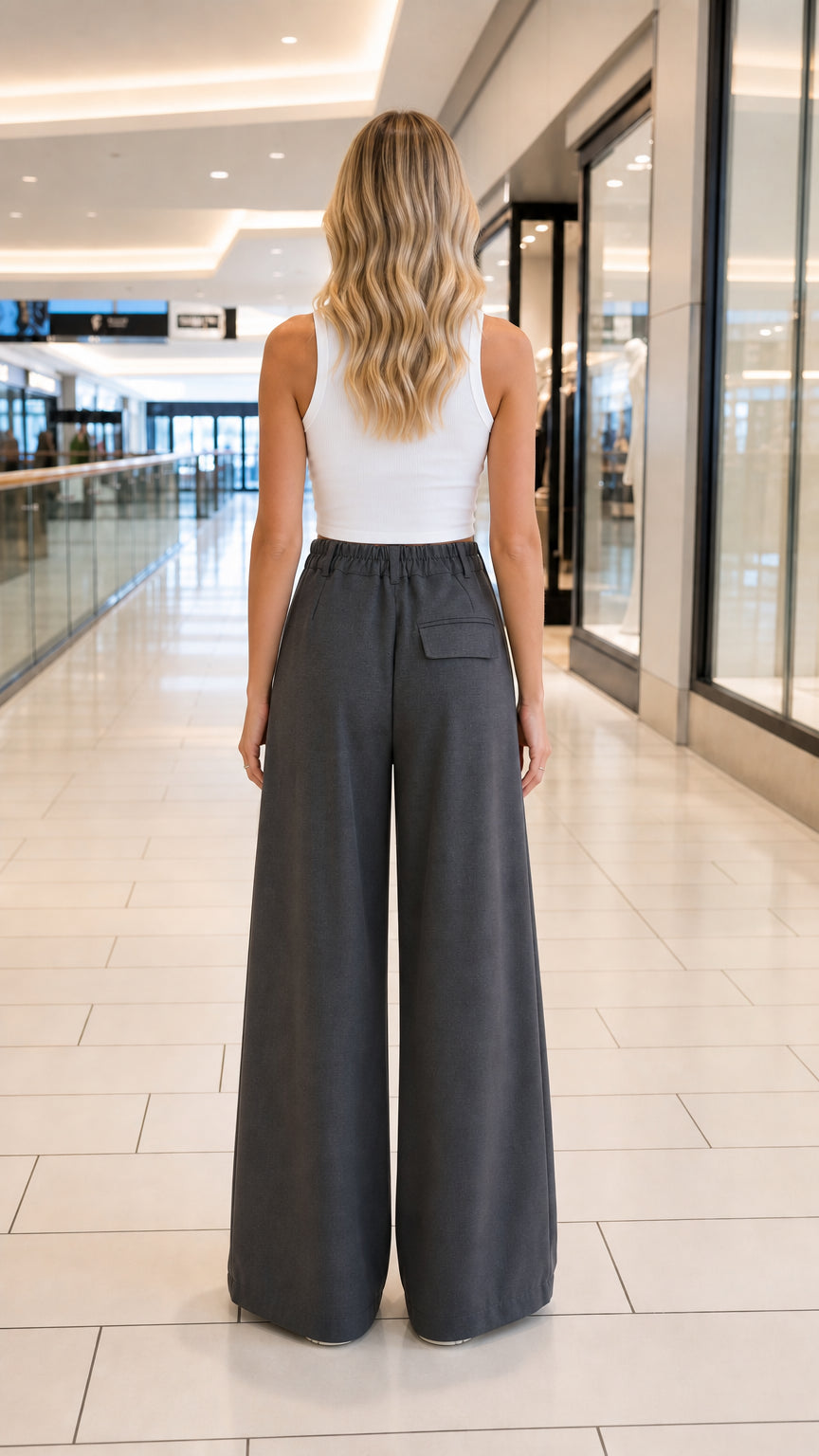 Back view of model wearing charcoal grey wide-leg trousers showing elasticated waistband