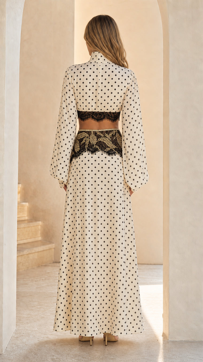 Back view of model in cream polka dot two-piece crop top and maxi skirt