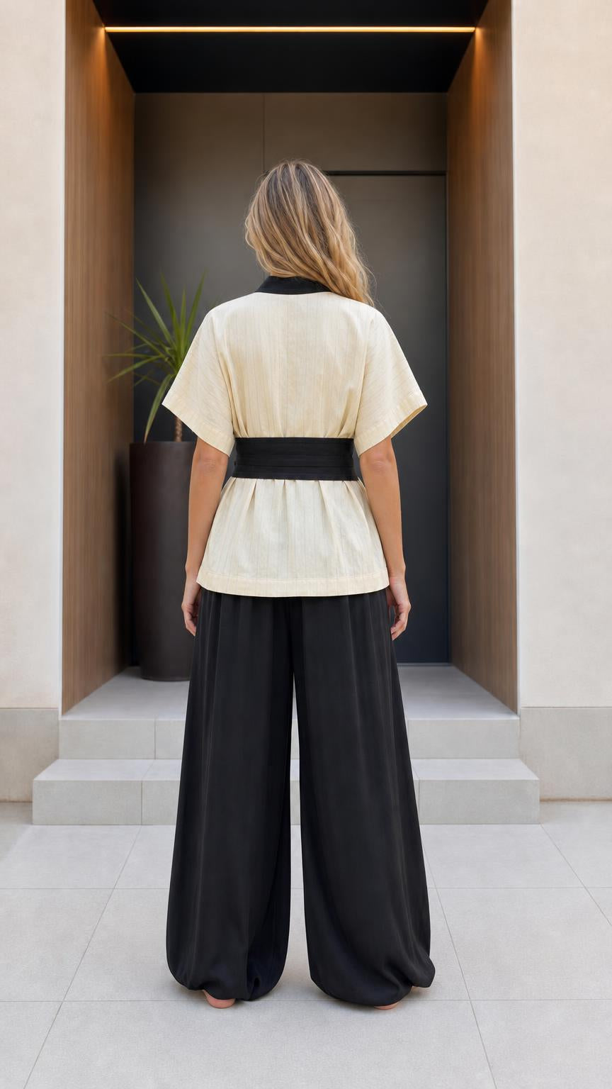 Back view of woman wearing beige kimono top and black pants