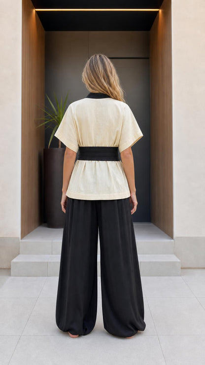 Back view of woman wearing beige kimono top and black pants