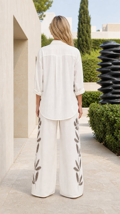 Back view of woman wearing white wide-leg trousers and shirt set