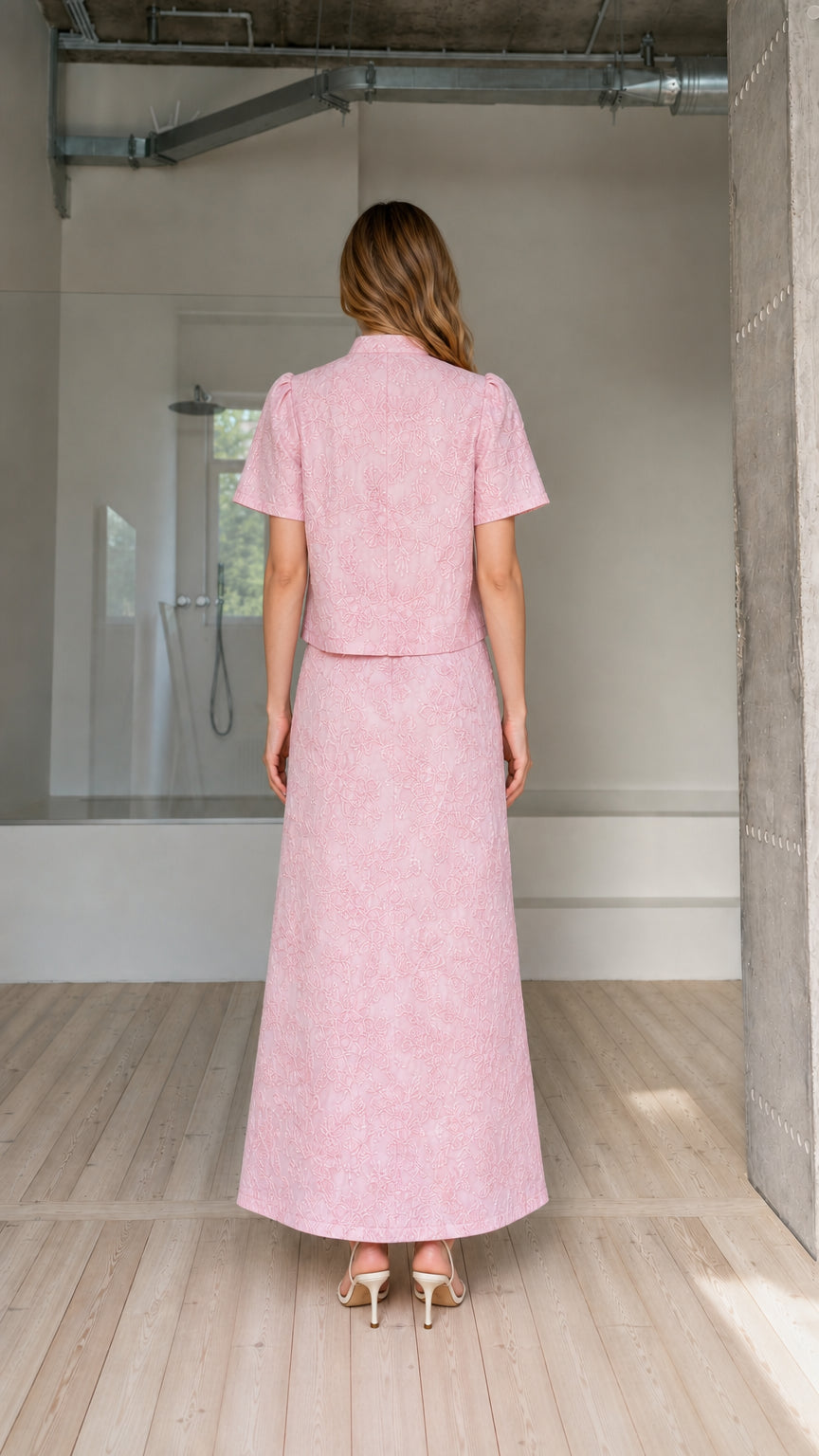 Back view of model wearing pink embroidered top and matching floor-length skirt