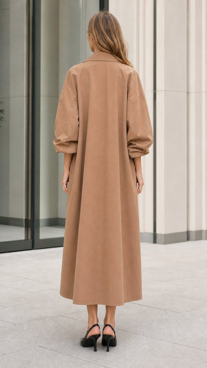 Back view of model showcasing the long sweeping silhouette of the camel trench coat