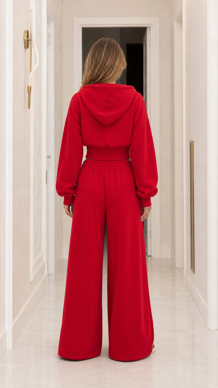 Back view of woman wearing red hooded cropped sweatshirt and wide-leg sweatpants