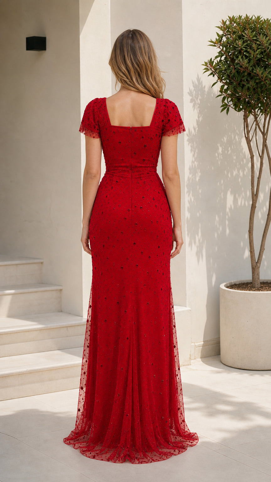 Back view of model showcasing the square back and sweeping hem of the red formal gown