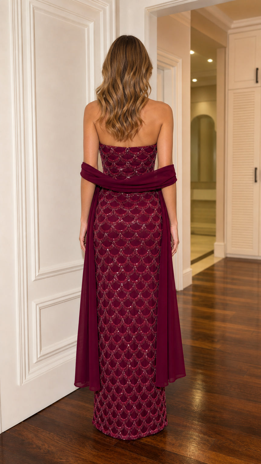 Back view of burgundy strapless sequin maxi gown with flowing cape