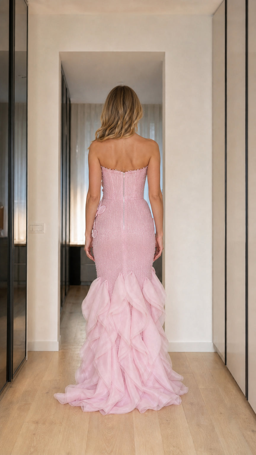 Model wearing pink strapless mermaid gown, back view showing ruffled train