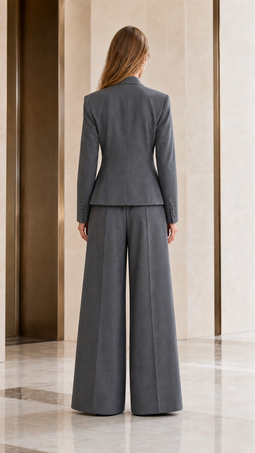 Back view of women's grey tailored pant suit highlighting sleek cut and structured shoulders