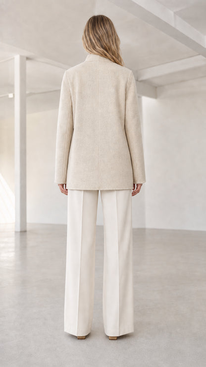 Back view of model showcasing clean back construction of cream stand collar coat
