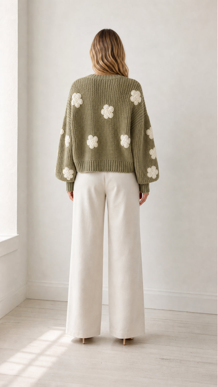 Back view of model wearing sage green chunky knit cardigan with white 3D flower patches