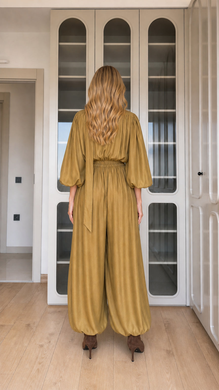 Back view of woman wearing mustard long sleeve draped jumpsuit