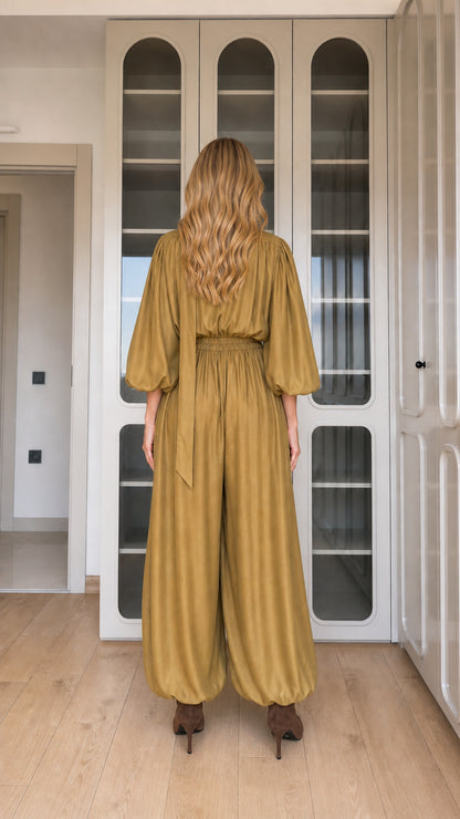 Back view of woman wearing mustard long sleeve draped jumpsuit