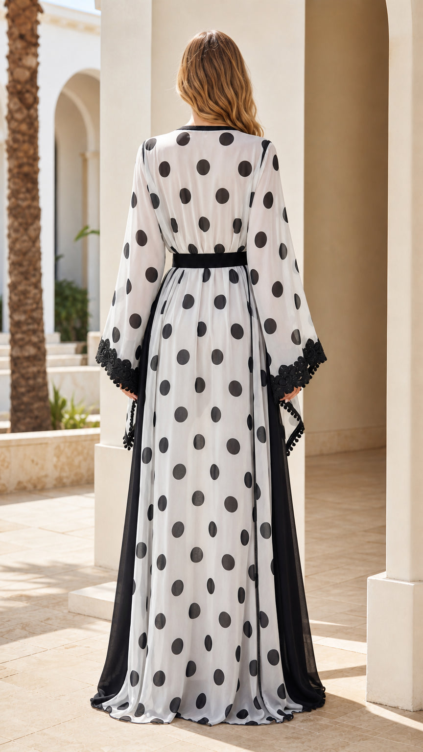 Back view of woman wearing floor-length white polka dot kaftan dress with belted waist