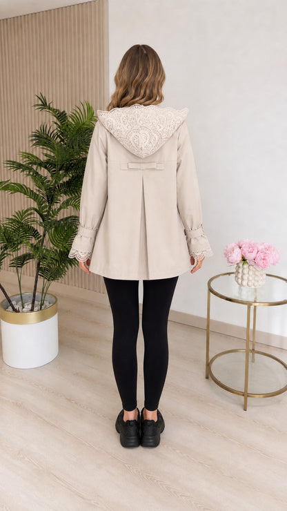 Back view of beige hooded coat showing lace hood trim and back bow pleat