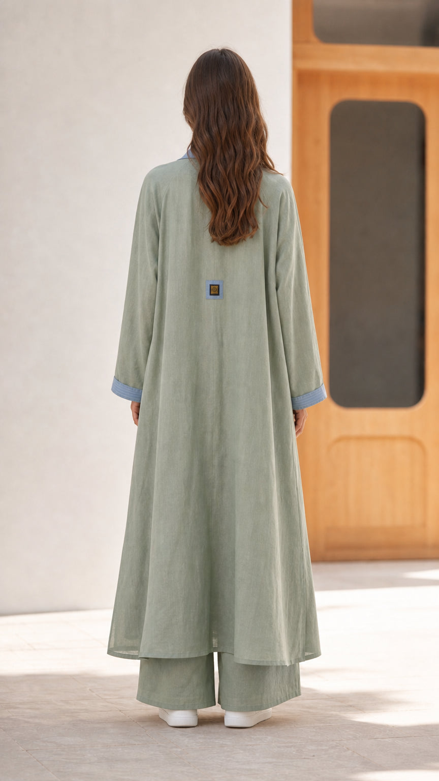 Back view of sage green long duster coat showing clean flowing silhouette