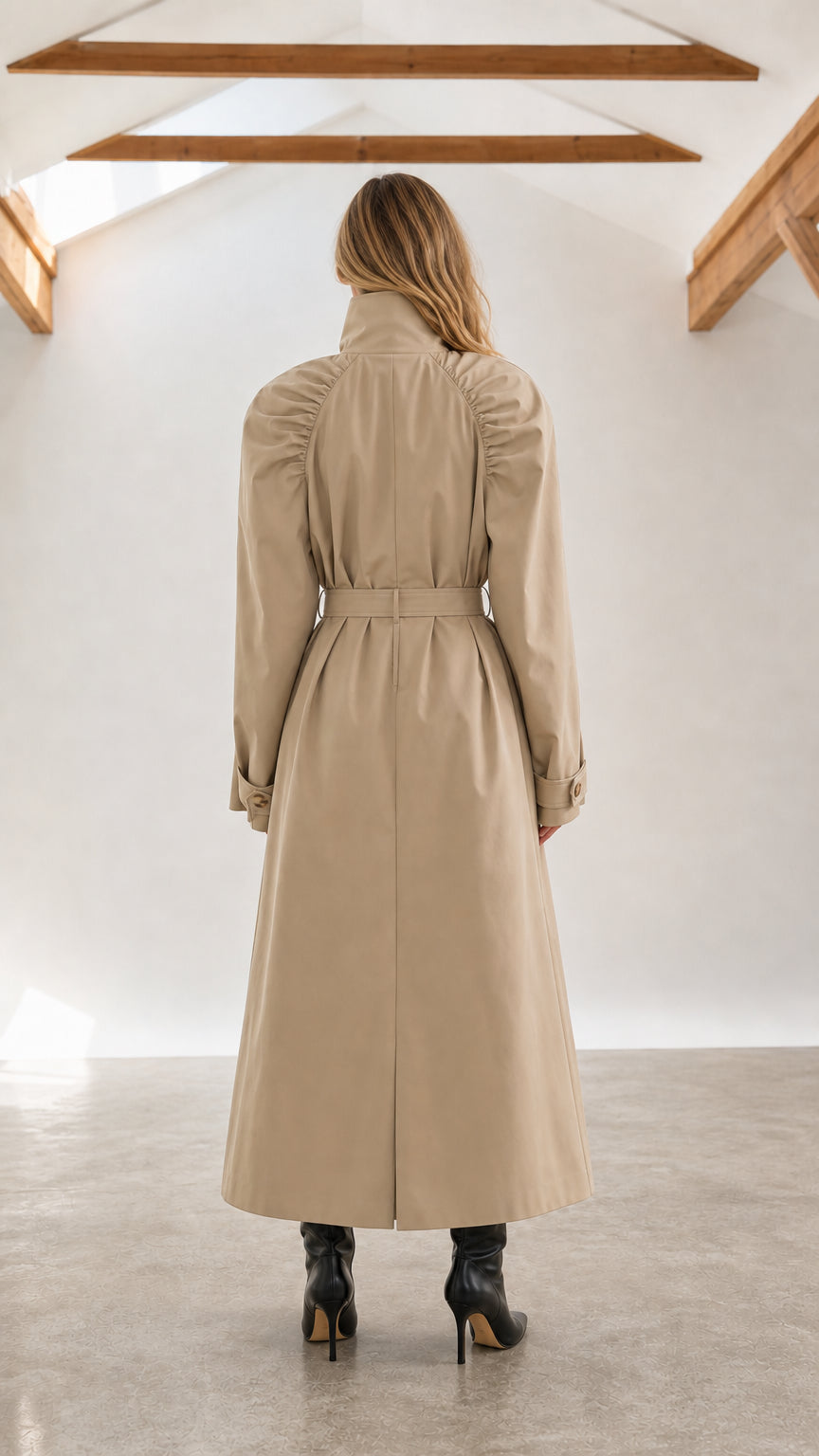 Back view of woman wearing beige full-length trench coat with ruched shoulders