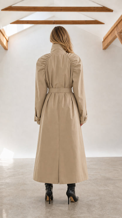 Back view of woman wearing beige full-length trench coat with ruched shoulders