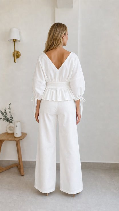 Back view of model in white peplum blouse and trousers